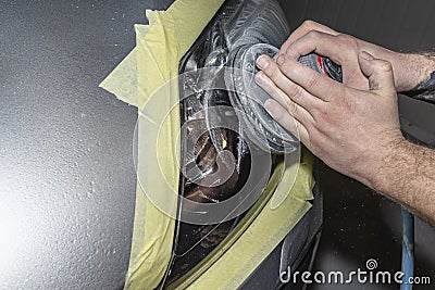 A car sprayer polishes the headlamp with a pneumatic sponge grinder. Stock Photo
