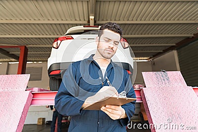 Car Technician Preparing Checklist In Workshop Stock Photo