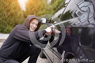 Car thief steal car breaking door criminal job burglar Hijacks Auto thief black balaclava hoodie trying break into vehicle Stock Photo