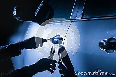 Car thief using a tool to break into a car Stock Photo