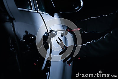 Car thief using a tool to break into a car Stock Photo