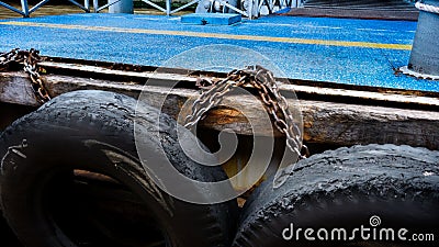 Car tire with metal chain on a old concrete sea pier,old truck tires at the pier.tire bumpers Stock Photo