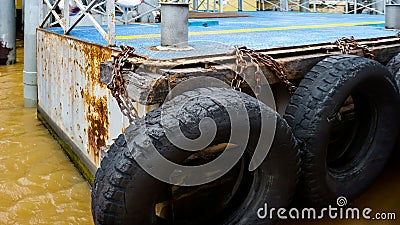 Car tire with a metal chain on old concrete sea pier,old truck tires at the pier.tire bumpers Stock Photo