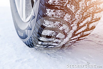 The car tire in the snow close up. Car tracks on the snow. Traces of the car in the snow. Winter tires. Tyres covered with snow at Stock Photo