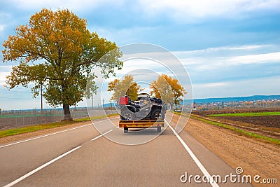 A car with a trailer loaded with ATVs is driving along a country road. Travel and tourism, recreation and entertainment Editorial Stock Photo