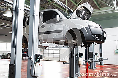 Car undergoing service in garage raised on lift Stock Photo