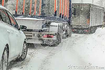 Car waiting behind large trucks during traffic jam on forest road, caused by heavy snow blizzard Stock Photo