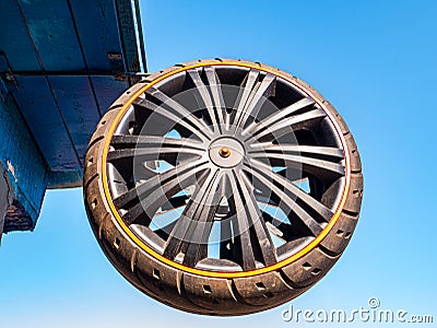 A car wheel attached to the roof of a building against the blue sky. Stock Photo