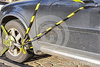 Car wheel is locked due illegal parking violation. Police equipment for blocking the car wheel of a parking Stock Photo