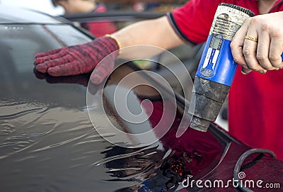 Car window tinting specialist attaching Tinting Film to car rear windscreen. Editorial Stock Photo