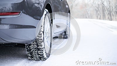 Car on the Winter Road. Close-up Image of Winter Car Tire on the Snowy Road. Safe Driving Concept. Stock Photo