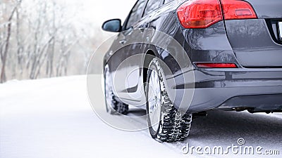 Car on the Winter Road. Close-up Image of Winter Car Tire on the Snowy Road. Safe Driving Concept. Stock Photo