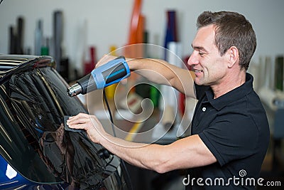 Car wrapper using heat gun and squegee for tinting window Stock Photo