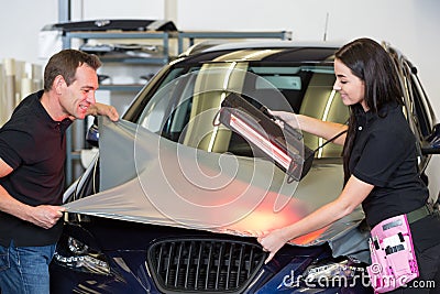 Car wrappers using red light lamp to flatten vinyl film Stock Photo