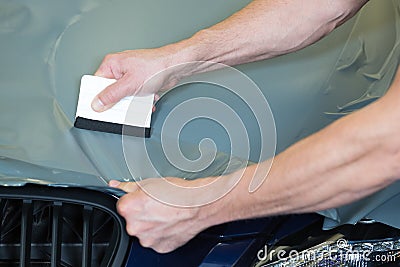 Car wrappers using squeegee to straighten vinyl film Stock Photo