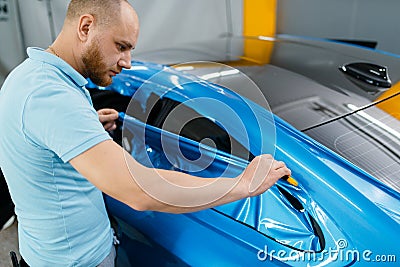 Car wrapping, mechanic cuts vinyl foil or film Stock Photo