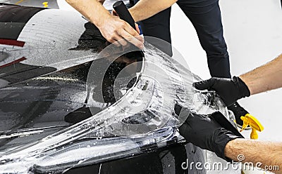 Car wrapping specialist putting vinyl foil or film on car. Protective film on the car. Applying a protective film to the car with Stock Photo