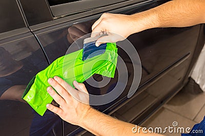 Car wrapping specialist wraps car door handle with adhesive foil or film Stock Photo