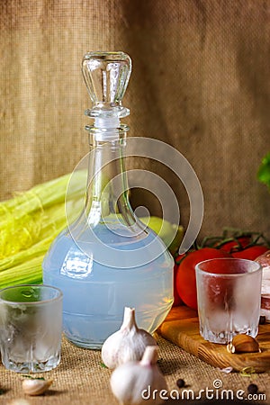 A carafe of vodka glasses the vegetables and bacon are on the table Stock Photo