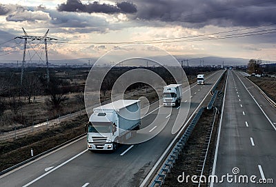 Caravan or convoy white lorry trucks on country highway Stock Photo