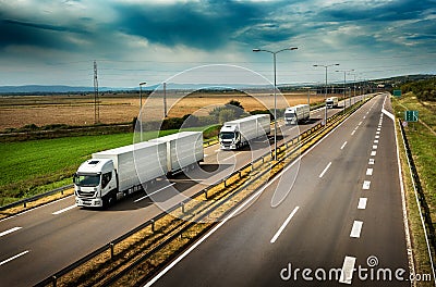 Caravan or convoy of White Lorry trucks on highway Stock Photo