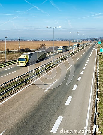 Caravan or convoy of Yellow lorry trucks on country highway Stock Photo