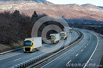 Caravan or convoy of Yellow lorry trucks on country highway Stock Photo