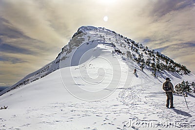 A caravan of mountaineers climbing a beautiful mountain with snow and sun rays. Pico Pia Paxaro, Courel, Galicia Editorial Stock Photo