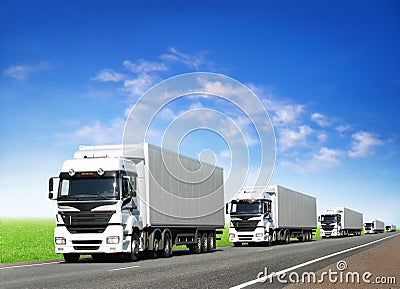 Caravan of white trucks on highway under blue sky Stock Photo