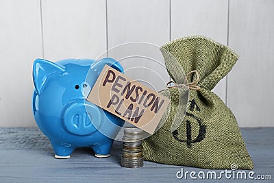 Card with phrase Pension Plan, stack of coins, sack and piggy bank on light blue wooden table. Retirement concept Stock Photo
