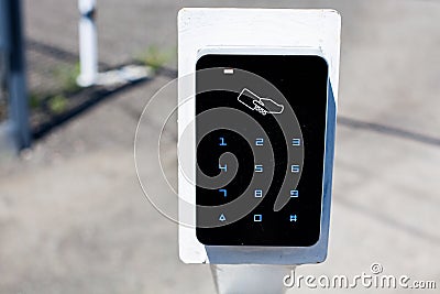 A card reader for access cards for entering the parking lot, in the background there is a white barrier Stock Photo