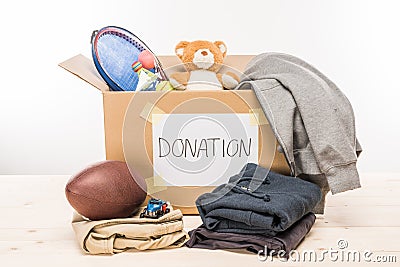 Cardboard box with donation clothes and different objects on white Stock Photo