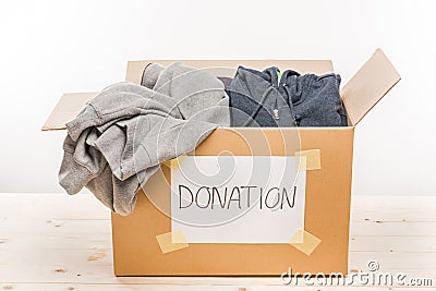 Cardboard box with donation clothes on wooden table on white Stock Photo