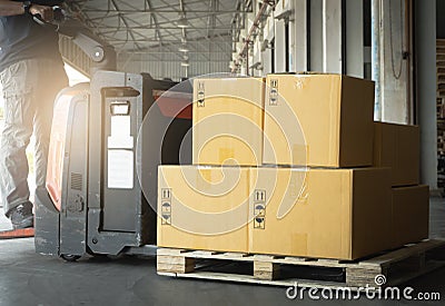 Cardboard boxes on Wooden Pallet with Worker Driving Electric Forklift Pallet Jack Unloading at The Warehouse. Package Boxes. Stock Photo