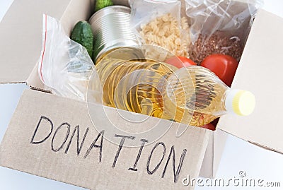 Cardboard donation box with food on white background close-up. Cereals, oil, canned food, vegetables in it. Donation and charity Stock Photo