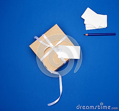 Cardboard gift square box tied with a white thin ribbon and white empty card Stock Photo