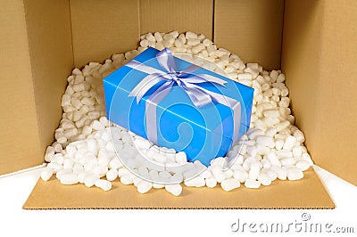 Cardboard shipping delivery box with blue gift inside and polystyrene packing pieces, front view Stock Photo