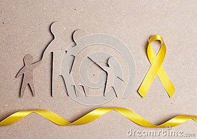 Cardboard silhouette of a family with yellow awareness ribbon on cardboard background Stock Photo