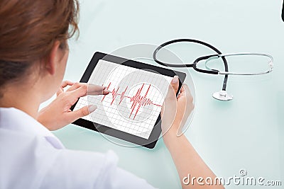 Cardiologist Analyzing Heartbeat On Digital Tablet Stock Photo