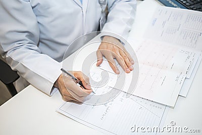 cardiologist doctor looking at electrocardiograph ekg paper filling patient form Stock Photo