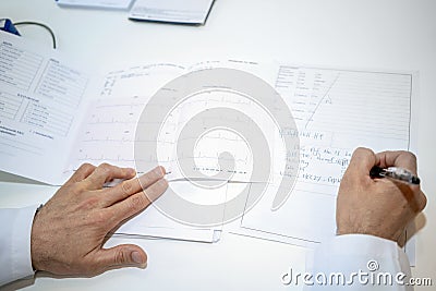 cardiologist doctor looking at electrocardiograph ekg paper filling patient form Stock Photo