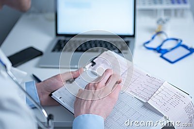 Cardiologist reading an ECG print-out. Doctor analyzing electrocardiogram. Practitioner examine patient test results Stock Photo