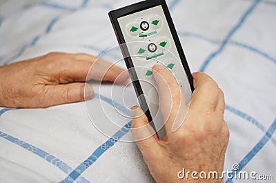 Care-dependent person holding bed remote Stock Photo