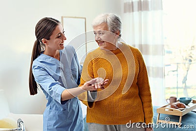 Care worker helping elderly woman to walk in hospice Stock Photo