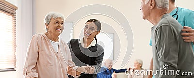 Care workers helping to elderly patients to walk in geriatric hospice Stock Photo