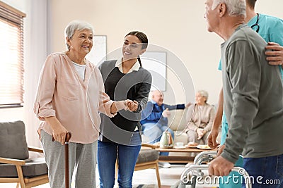 Care workers helping to elderly patients to walk in hospice Stock Photo