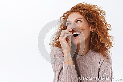 Carefree, arrogant and self-assured elegant, funny redhead woman with curly hair holding strand and put it under nose to Stock Photo