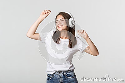 Carefree attractive girl dancing and listening music in wireless headphones Stock Photo