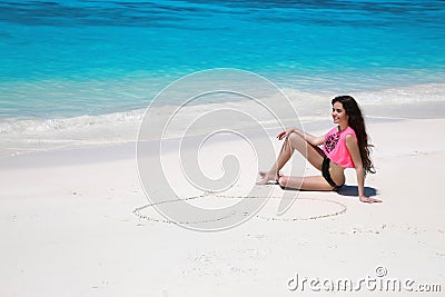 Carefree bikini model girl with heart on sand relaxing on exotic Stock Photo