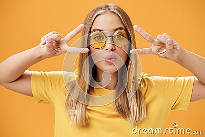 Carefree charismatic pretty woman in trendy round sunglasses and t-shirt folding lips in kiss showing peace or disco Stock Photo